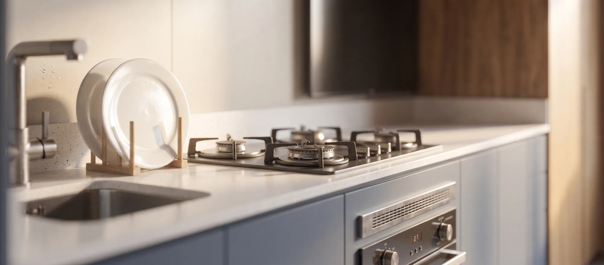 Cozinha com bancada clara, cooktop embutido e armários em tom azul acinzentado sob luz natural