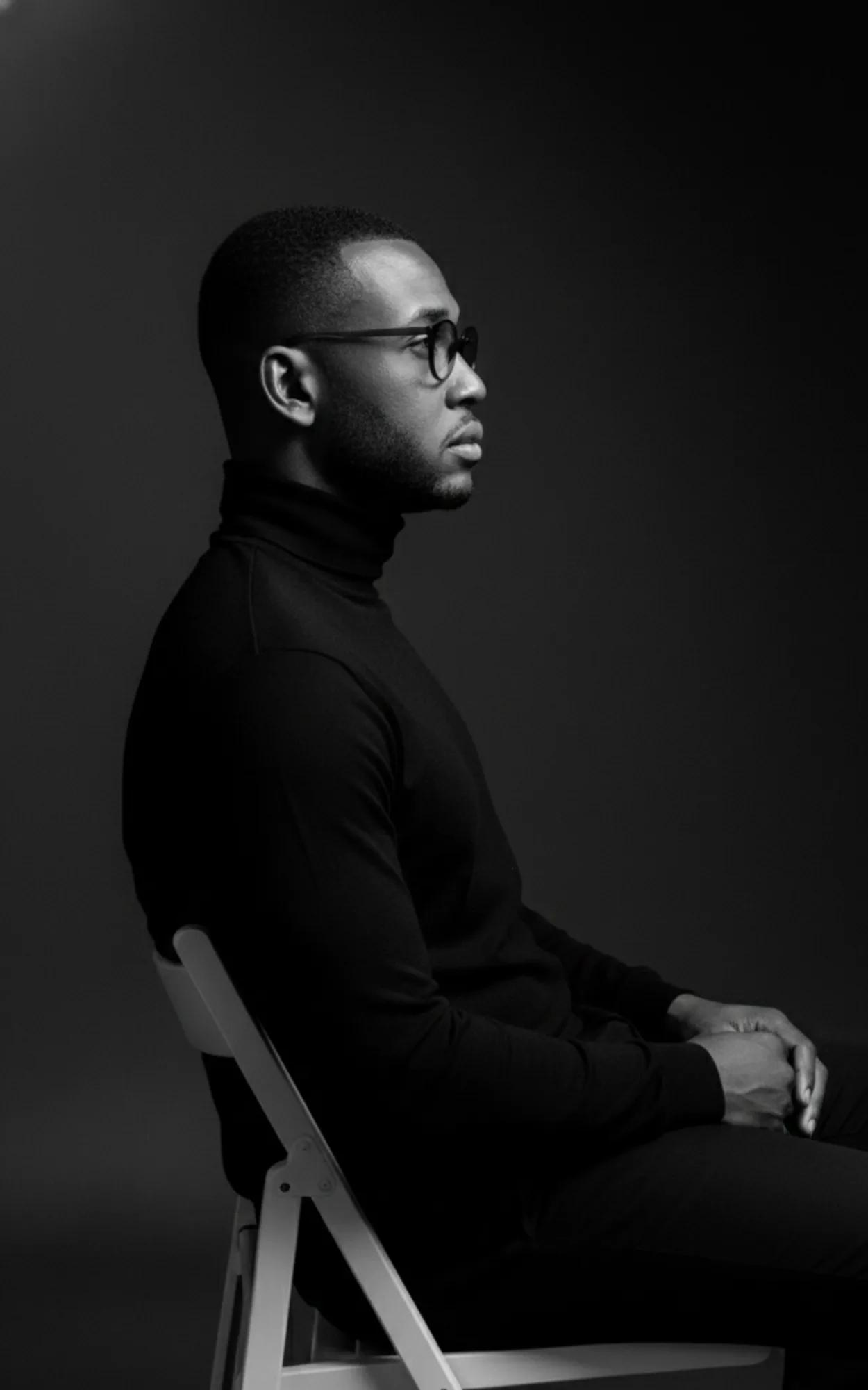 Retrato em preto e branco do arquiteto Mateus Felipe, sentado de perfil